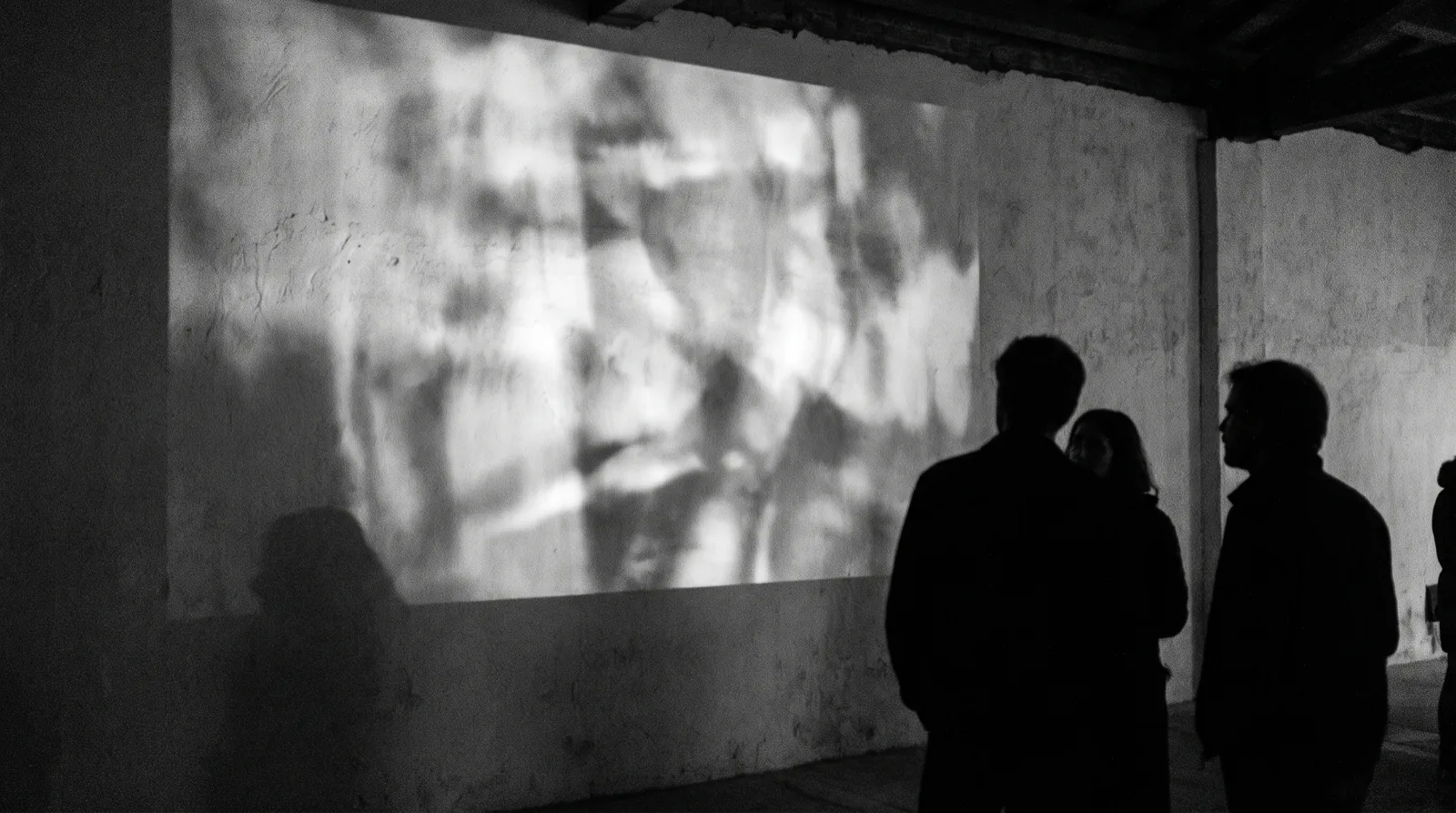 Eine großflächige Projektion an einer Wand in einem abendlichen Raum, davor Silhouetten von Gästen.